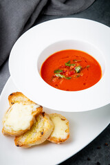 borscht with herbs in a white plate with pieces of bread, side view
