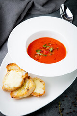 borscht with herbs in a white plate with pieces of bread, side view