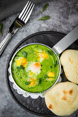 creamy broccoli soup in a frying pan with tortillas against a dark background, top view
