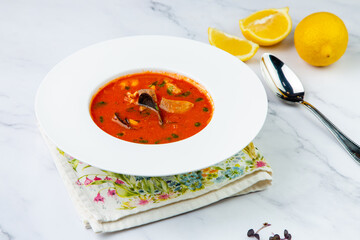 orange cream soup with pieces of meat in a white plate, side view