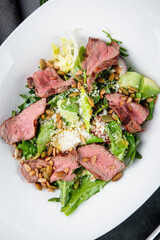 salad with pieces of beef, pistachios, lettuce and cheese side view