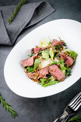 salad with pieces of beef, pistachios, lettuce and cheese side view
