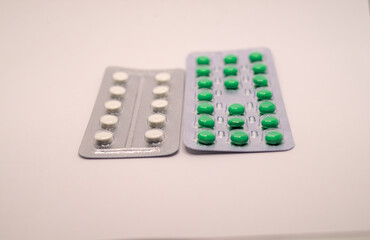 White and green pills in plastic package isolated
