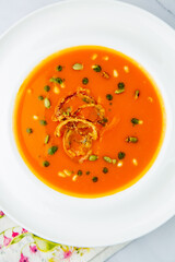 orange cream soup with pieces of meat in a white plate, top view