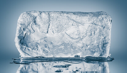 A big rectangular textured transparent piece of ice on a blue background. - obrazy, fototapety, plakaty