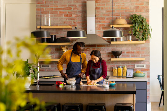 Happy diverse couple baking christmas cookies making dough in kitchen, copy space - Powered by Adobe