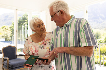 Happy caucasian senior couple holding passports and smartphone in sunny bedroom at home