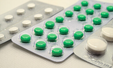 Medical pills in white and green colors close up