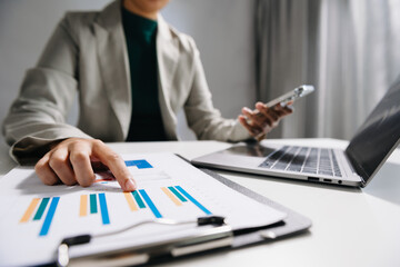 business documents on office desk with laptop and smart phone and graph business diagram and man working at office