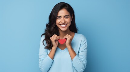 Hispanic woman standing over blue background smiling lovingly and making heart symbol shape with hands. romantic concept. I love you. Valentine's day  - obrazy, fototapety, plakaty