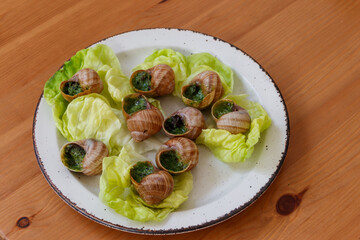Escargots de Bourgogne (snails) seasoned with butter, parsley, garlic on wooden table