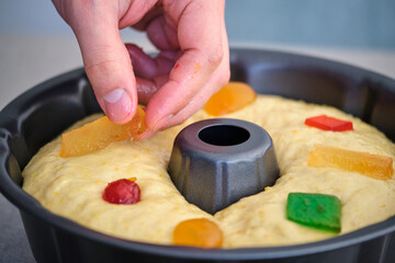 Hand putting candied fruit on a raw Roscon de Reyes. Typical spanish sweet for Christmas and kings...