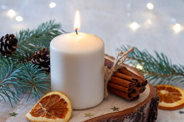Christmas decoration with candle, spruce twig, cinnamon and dried orange