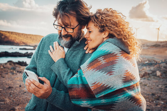 Man and woman using mobile phone connection online in outdoor travel leisure activity together. Happy adult couple enjoy technology and roaming communication. Travel adventure vacation lifestyle