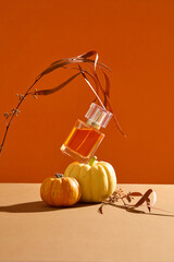 Concept of Autumn with a glass bottle of perfume stacked on a pumpkin. Front view. Blank label for...
