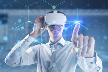 Attractive happy man with VR glasses pointing at creative glowing hexagonal pattern with tiny...
