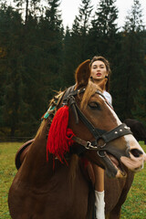 Young women ride horses in national Ukrainian dresses in the Carpathian mountains. Photo session with horses in the mountains. Ukrainian culture concept