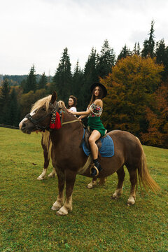 Young women ride horses in national Ukrainian dresses in the Carpathian mountains. Photo session with horses in the mountains. Ukrainian culture concept