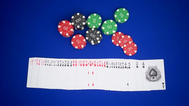 Poker Dealer Croupier Shuffling Playing Cards Opening The Deck On The Blue Table Next To Many Casino Chips