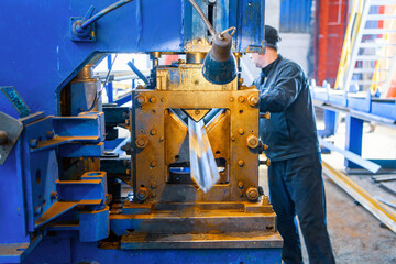 A hydraulic machine at a plant for bending sheet metal. Industrial worker out of focus working on a...