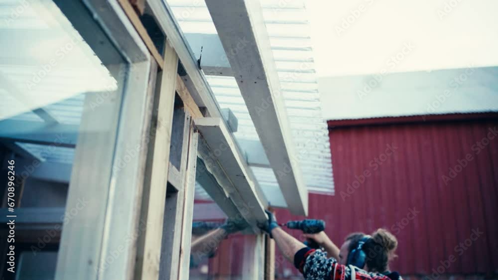 Poster man at work assembling window frame with cordless electric drill. static