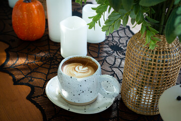 Halloween celebrated coffee,Close up of Hot coffee latte with latte art milk foam in cup mug with decor in a coffee a theme of halloween on wood desk Halloween holiday background.