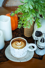 Halloween celebrated coffee,Close up of Hot coffee latte with latte art milk foam in cup mug with decor in a coffee a theme of halloween on wood desk Halloween holiday background.