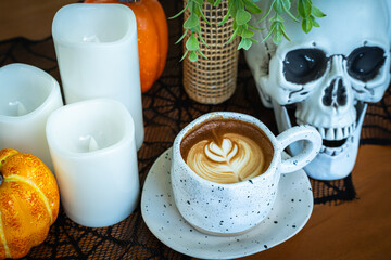 Halloween celebrated coffee,Close up of Hot coffee latte with latte art milk foam in cup mug with decor in a coffee a theme of halloween on wood desk Halloween holiday background.