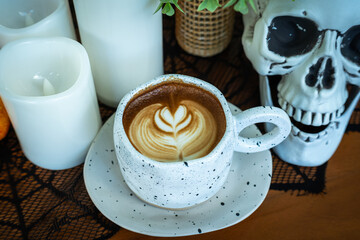 Halloween celebrated coffee,Close up of Hot coffee latte with latte art milk foam in cup mug with decor in a coffee a theme of halloween on wood desk Halloween holiday background.