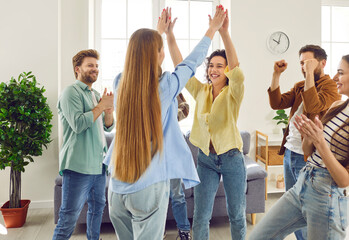 Portrait of a group of excited happy young friends students greeting each other giving high five during meeting at home. Smiling people men and women enjoying time together at the party. - obrazy, fototapety, plakaty