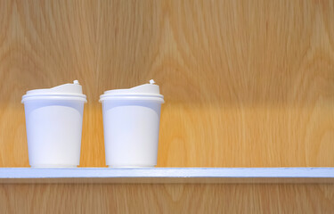 Two white double wall paper hot coffee cup mockup with plastic lid on wooden shelf, close up with copy space