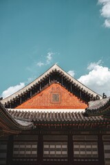 an orange brick building with some white windows in front of blue skies