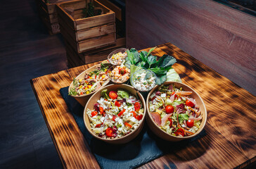 Different types of salads in a bowl on a wooden table in a restaurant.