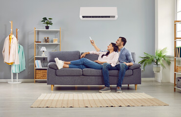 Young family couple enjoying life in their apartment with a modern air conditioning system. Happy...