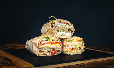 Sandwiches with salad, salami, cheese and dressing on black background.