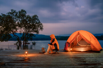 Solo Female Travelers Camping on Wooden Pier, Sit Relaxing with a Natural Reservoir Overview in the...