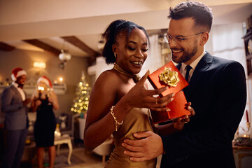 Happy man surprising his black girlfriend with Christmas present.