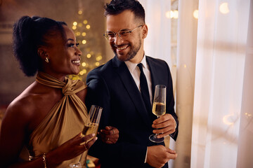 Happy man and his black girlfriend having glass of champagne on New Year's eve.
