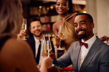 Happy black man toasting with friends while celebrating New Year.