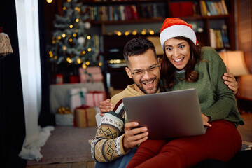 Cheerful couple has fun while making video call at Christmas at home.