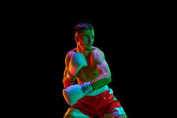 Shirtless boxer, mixed martial art fighter who preparing to fight against black mode background in...