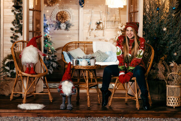 A girl in a Santa hat sits on the floor of a wooden house with garlands