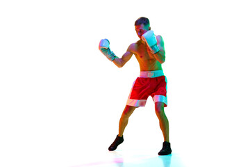 Fototapeta na wymiar Energetic young man, sportsman, boxer, fighter exercising before fight against white background in mixed neon filter, light.