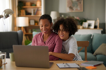 Mother and teenage son using a laptop at home