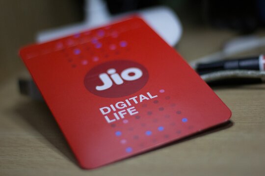 White Reliance Jio phone with a selection of credit cards beside it