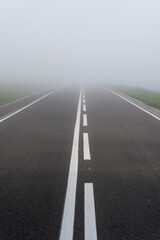 Asphalt road in the heavy fog with clear road markings, Pieniny mountains, Poland