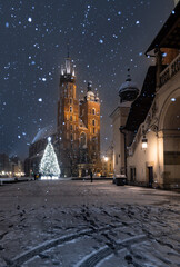 Krakow, Poland, snowy Main Market square, St Mary's church and Cloth Hall in the winter season,...