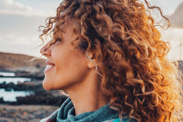 Woman outdoor smiling with long curly beautiful hair enjoying outdoor leisure activity alone....