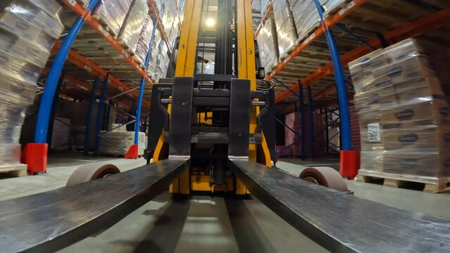 The forklift is moving through the warehouse. Specialized vehicles move around the warehouse. Forklift POV. point of view