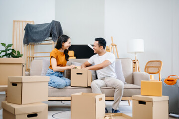 Fototapeta na wymiar Asian young attractive couple man and woman use tablet and smartphone online shopping furniture decorate house with carton package move in new house. Young married asian moving home. .
